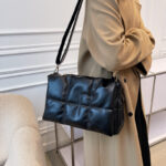 Woman wearing padded black shoulder bag soft flap